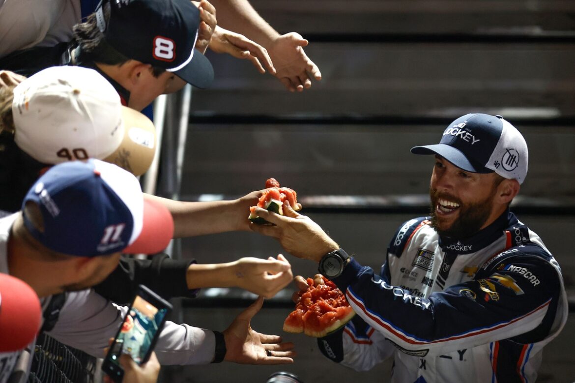 Ross Chastain prevents a fan from stealing his hat after victory at the Coke 600.
